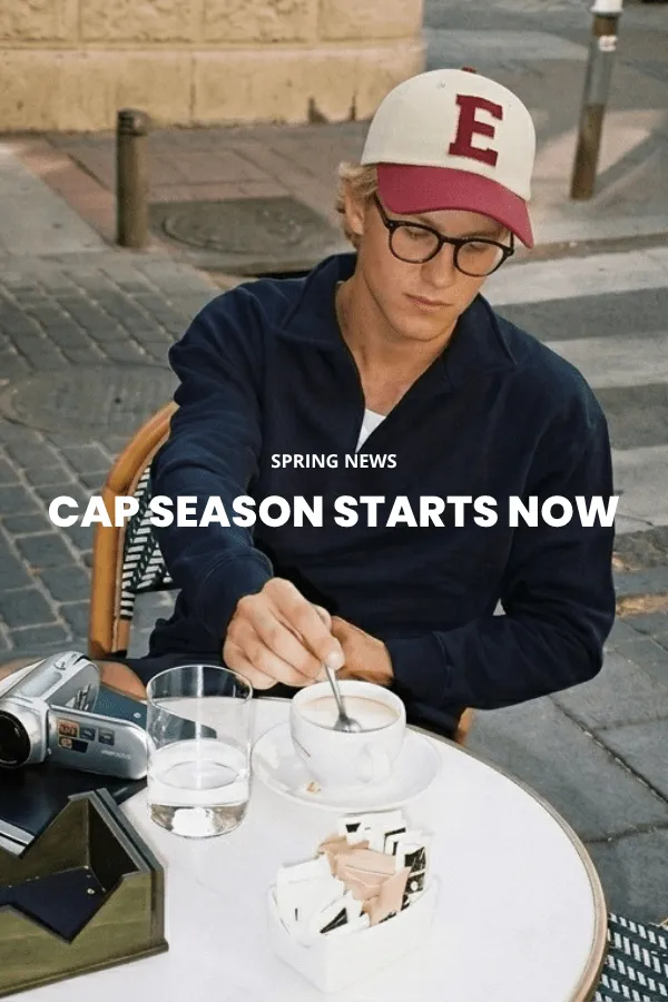 En mand sidder på en trækasse i et studie og bærer en klassisk brun cowboyhat i filt med bred skygge, en mørk denimskjorte og jeans.